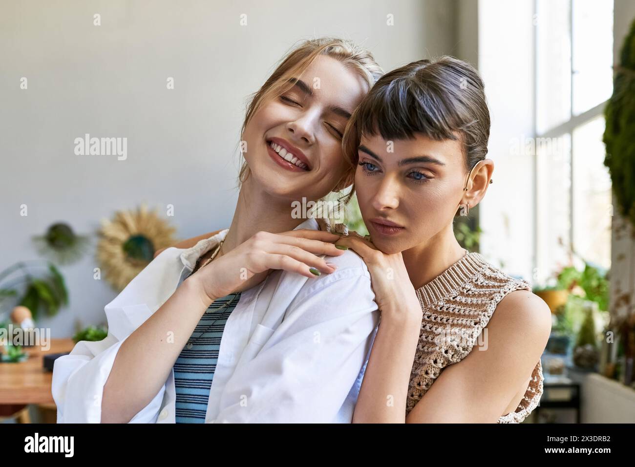 Two women, a tender loving lesbian couple, standing together in an art studio. Stock Photo