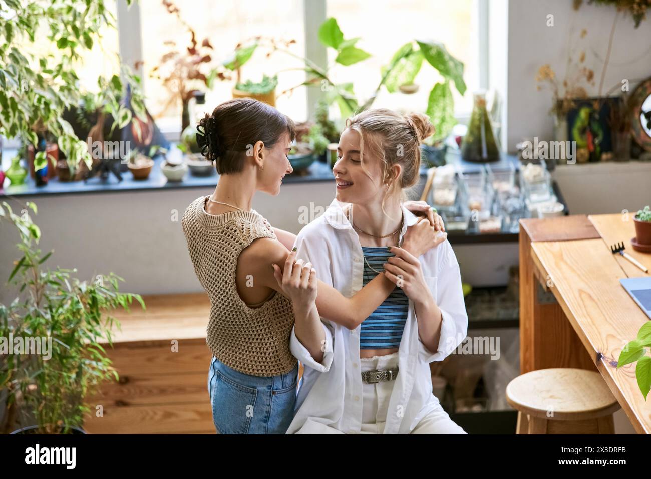 Two women, a loving lesbian couple, stand side by side in an art studio, exuding tender connection. Stock Photo