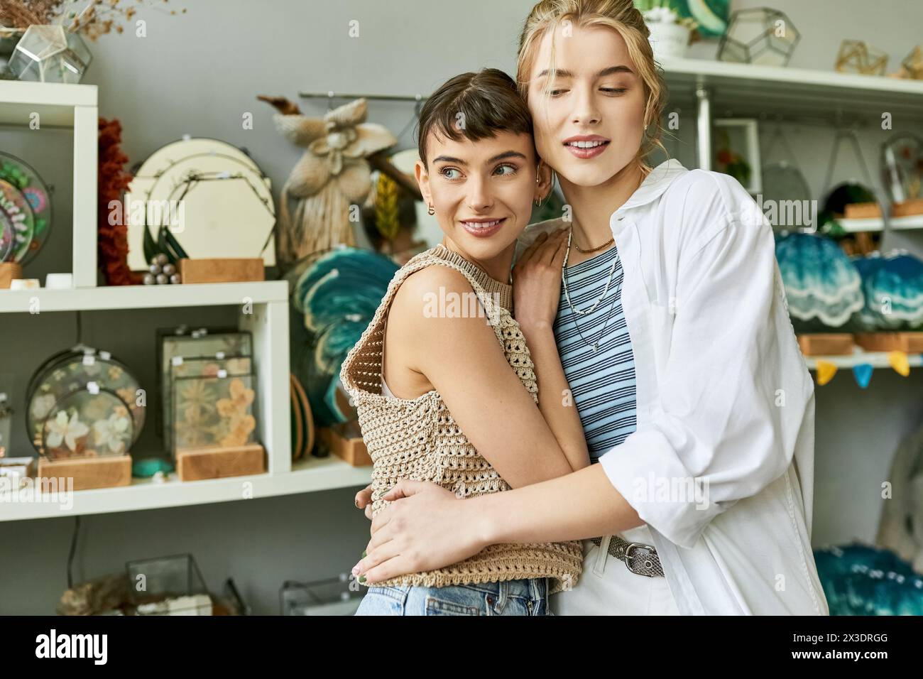 A loving lesbian couple, two women, standing in an art studio with a tender connection. Stock Photo