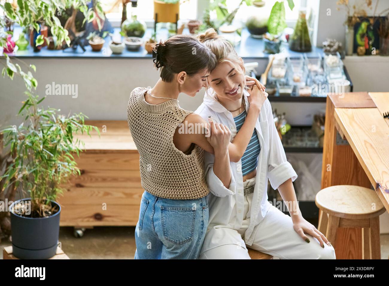Loving lesbian couple sitting closely, sharing creative moment in art studio. Stock Photo