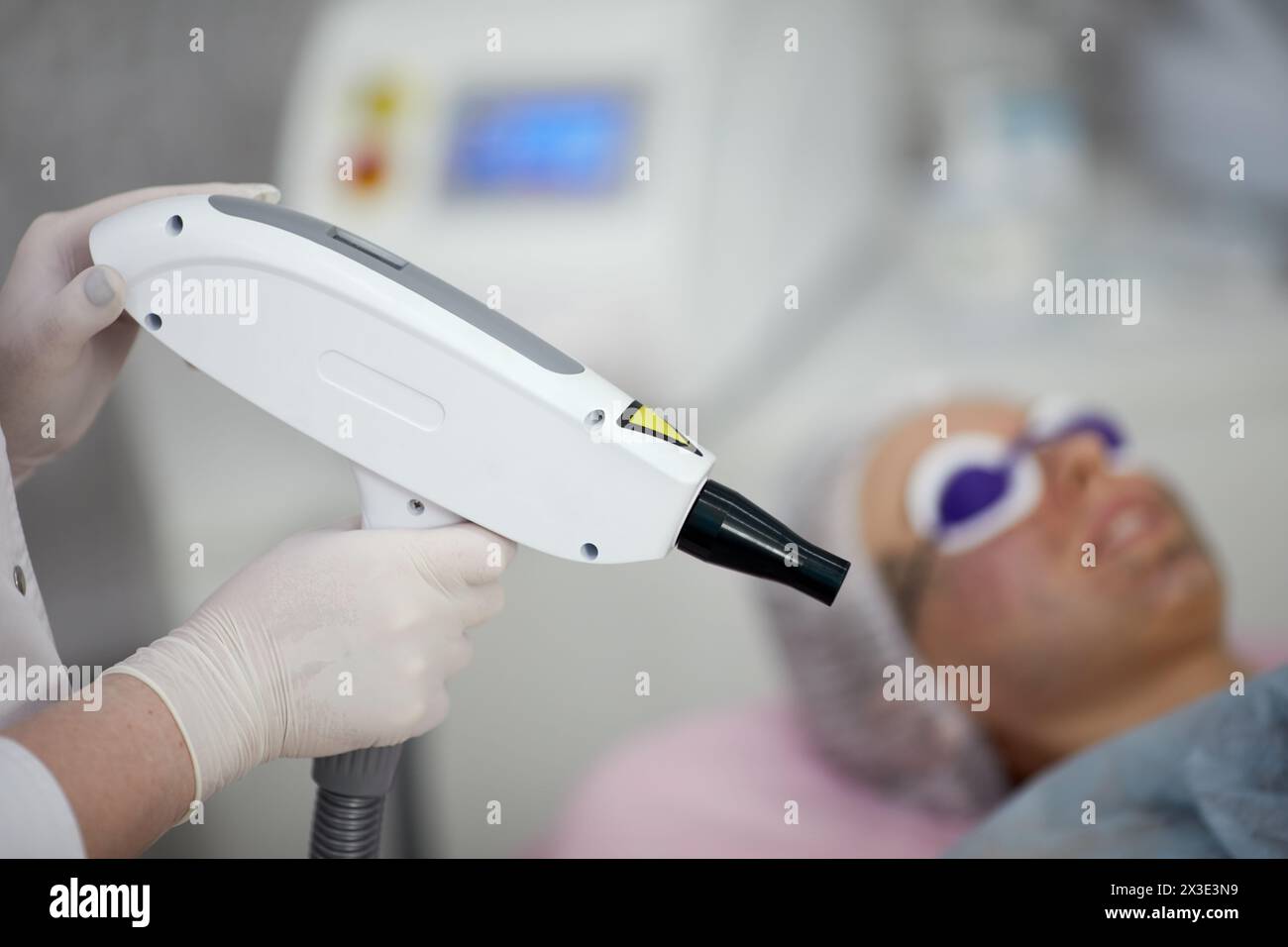 Beautician holds laser for epilating patient face, shallow dof, focus on laser. Stock Photo