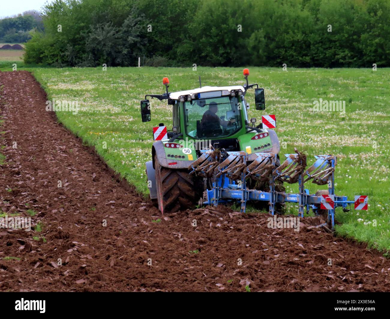 Ein Landwirt bricht mit seinem Ackerschlepper und Wendepflug eine sehr große Feuchtwiese um, wohl selbige dann in Ackerland gewandelt wird. Umbruch einer Wiese *** A farmer breaks up a very large wet meadow with his tractor and reversible plow, which is then converted into farmland. Stock Photo