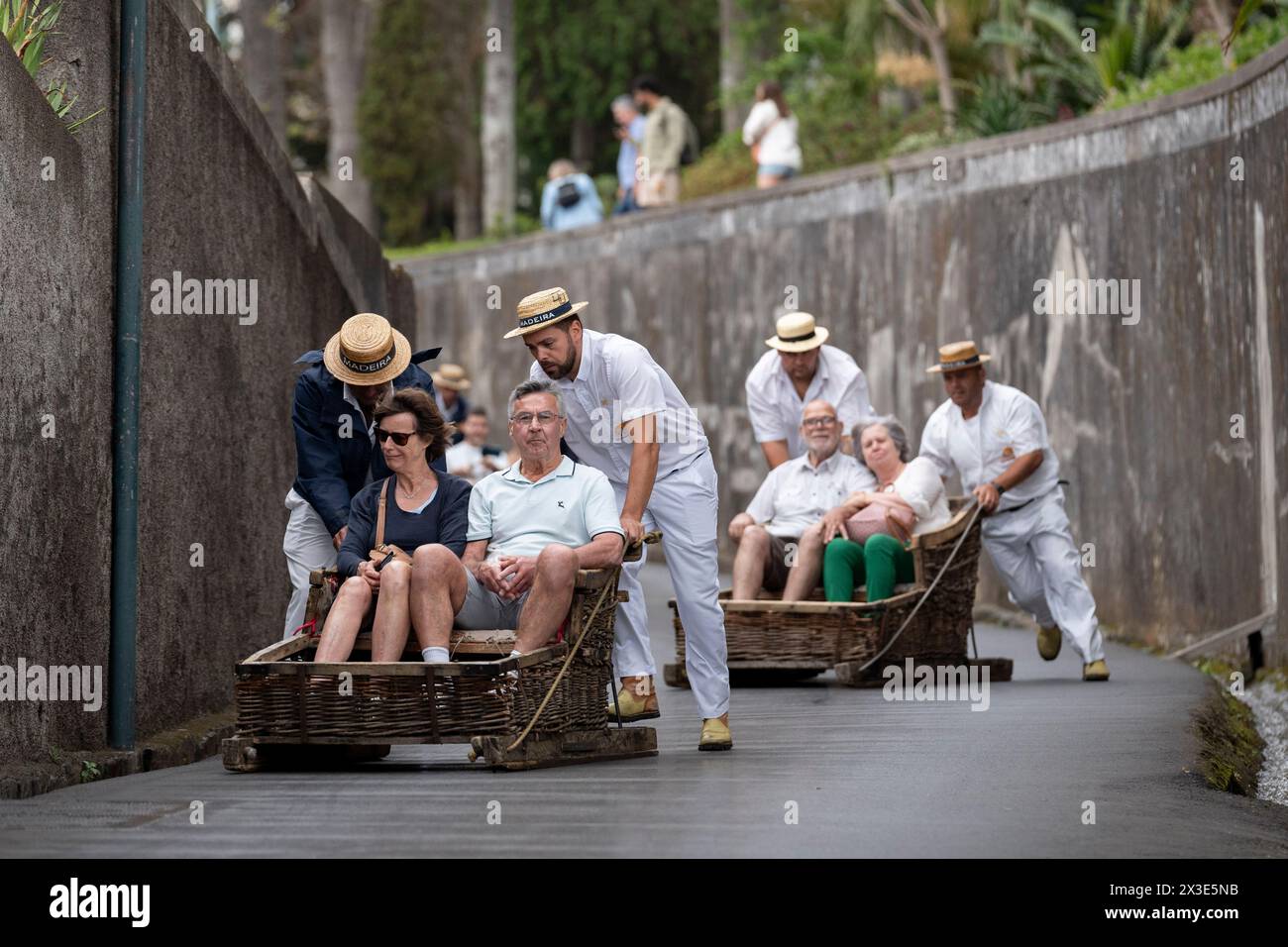 Tourist passengers ride Funchal's famous 'Carreiros de Monte' toboggan ride, on 19th April 2024, in Funchal, Madeira, Portugal.  (Extended caption in Additional Information). Stock Photo