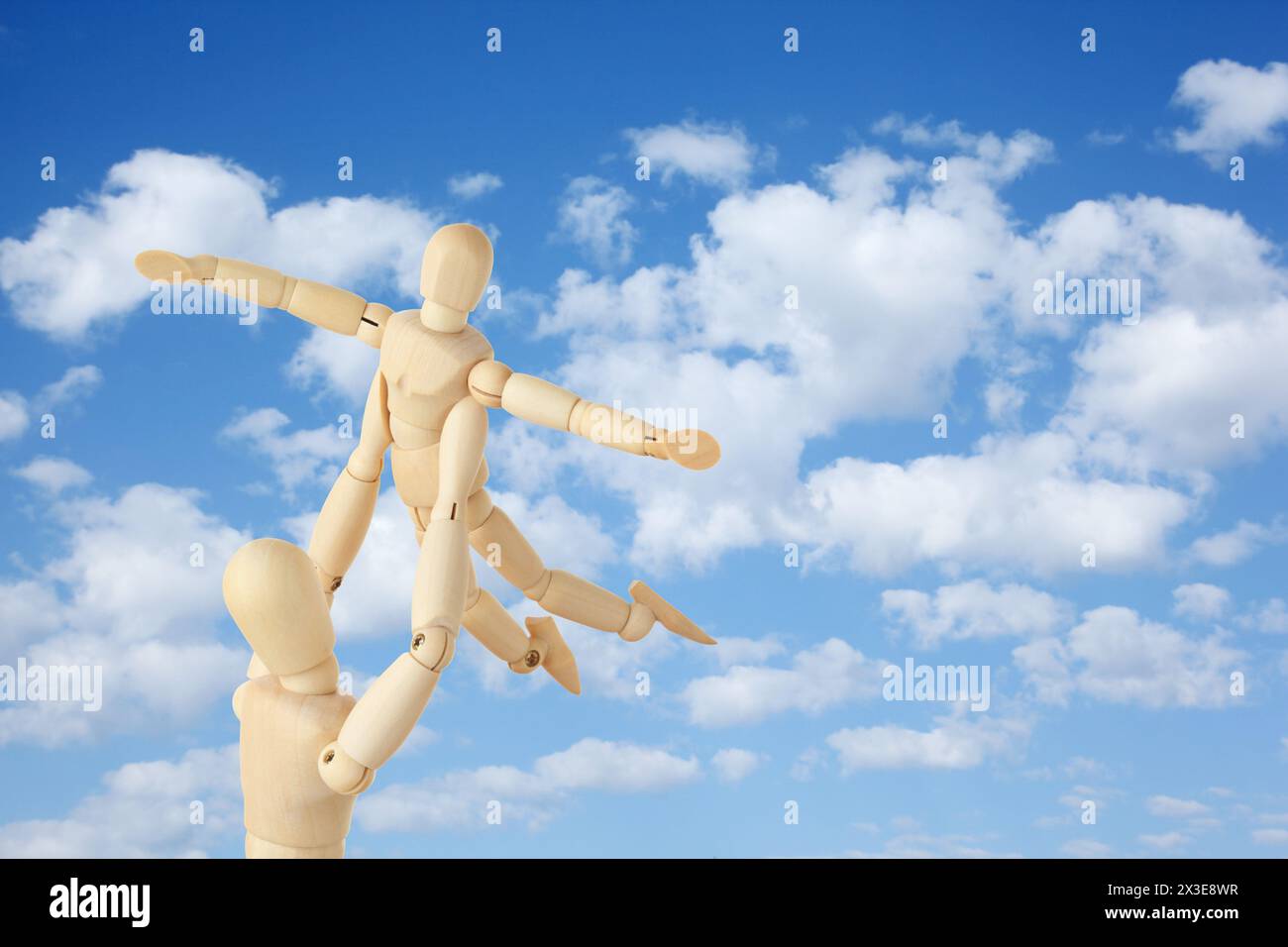 Wooden figures of parent carring his child over his head on sky background, collage Stock Photo