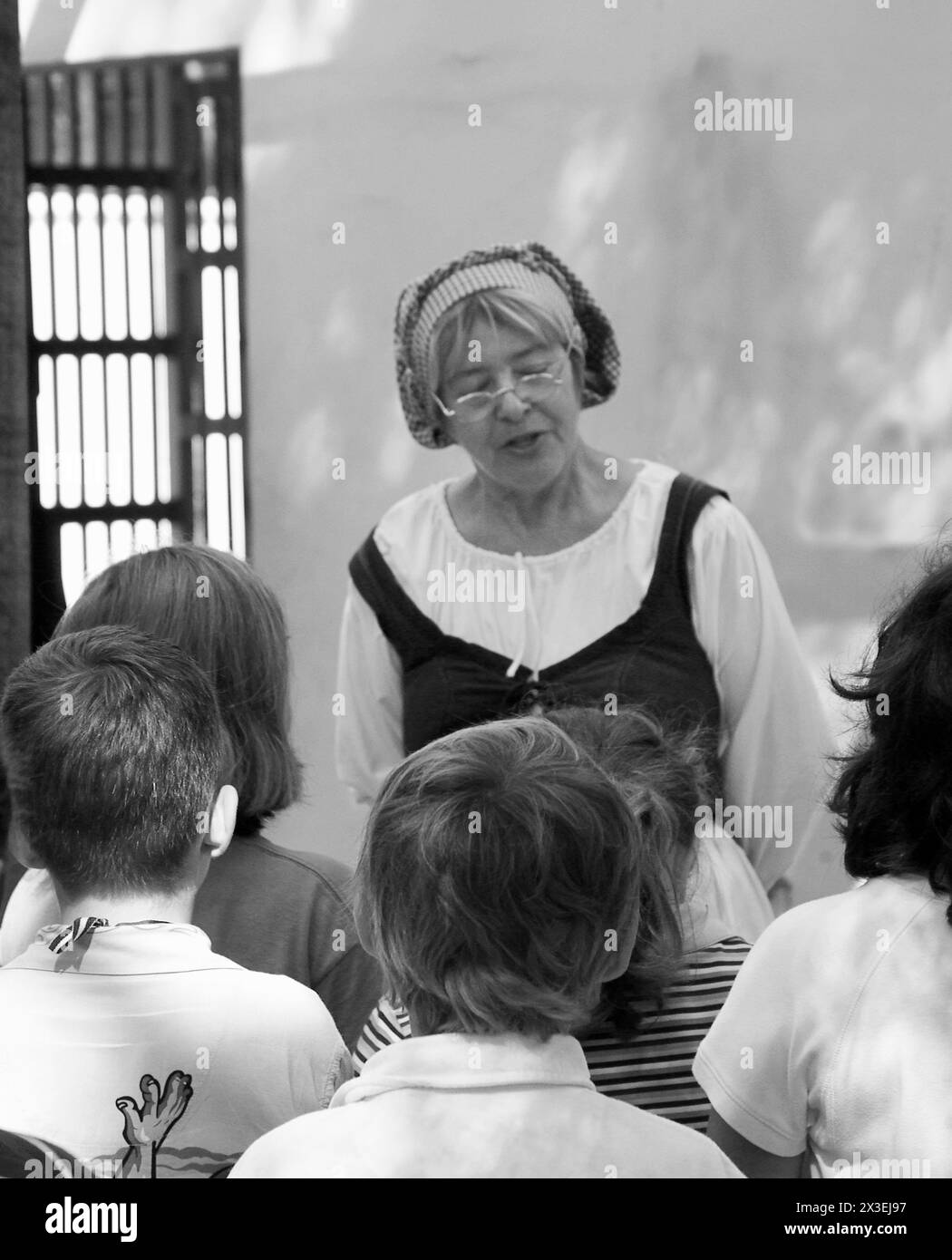 Woman wearing colonial clothing teaching children Black and White Stock ...