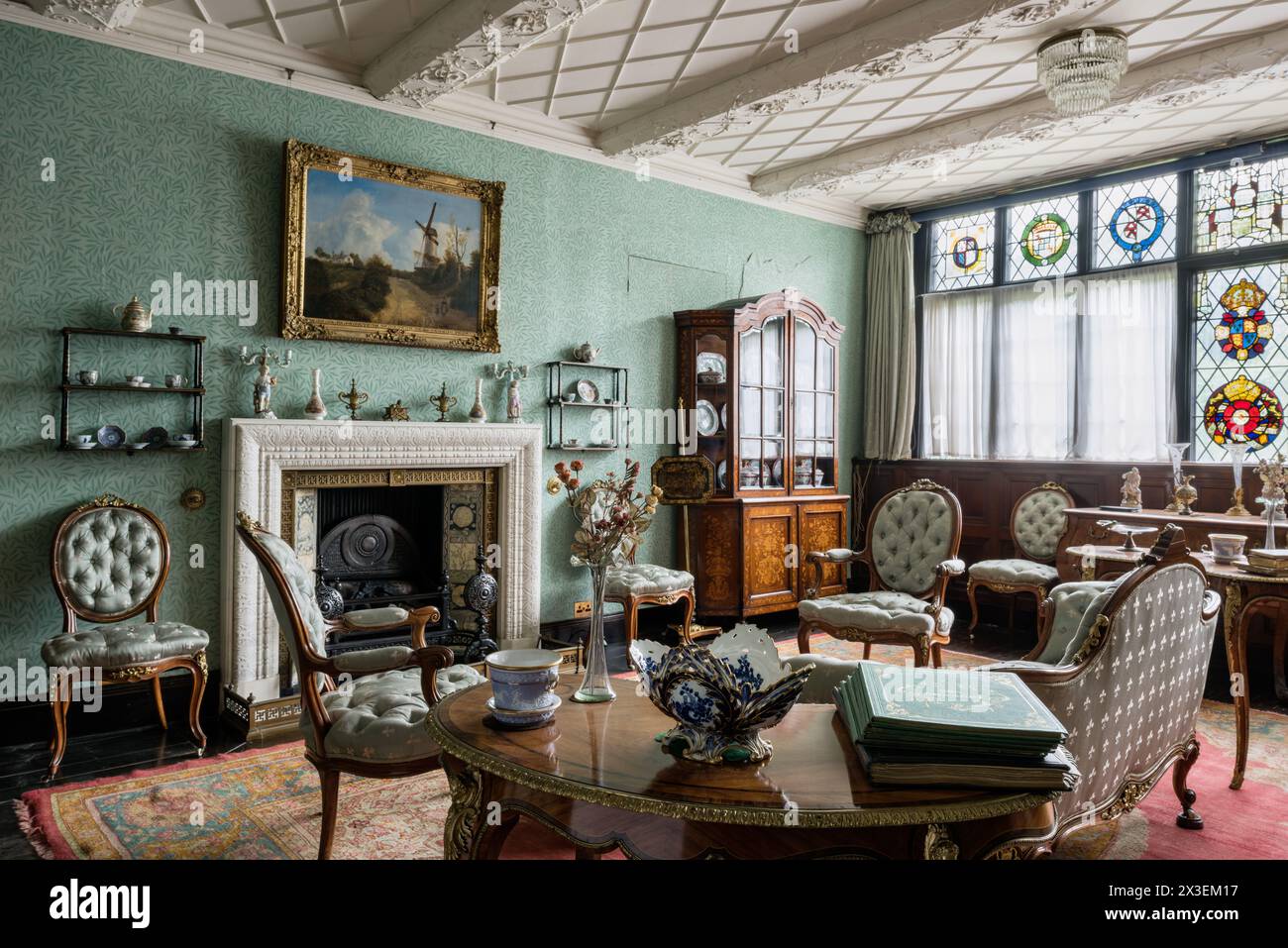 Antique furniture and stained glass windows in drawing room at Speke Hall, Grade I listed National Trust Tudor manor house,  Liverpool, England, UK. Stock Photo