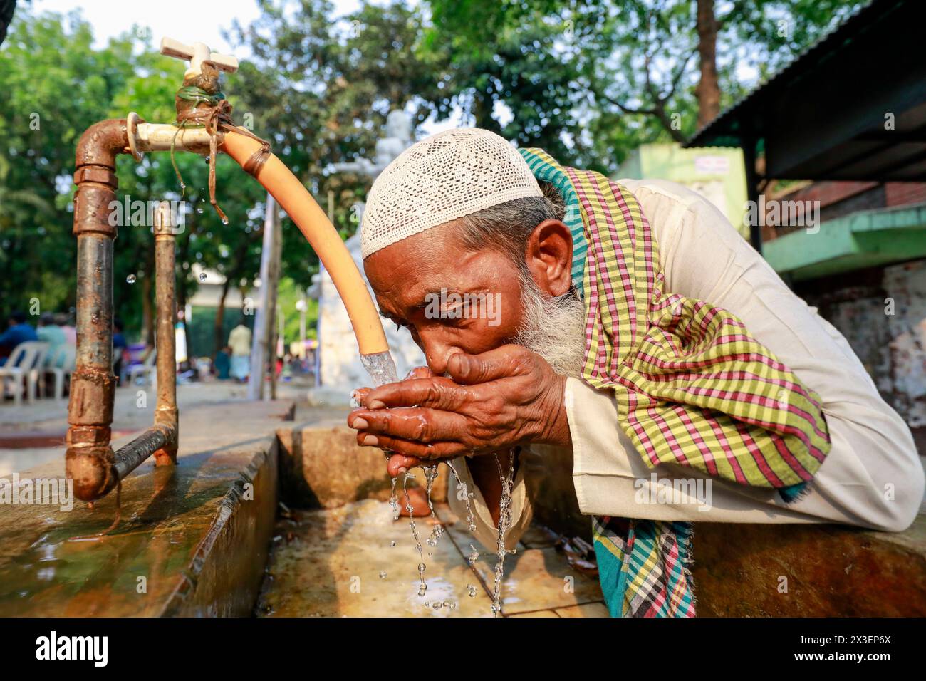 April 26, 2024, Dhaka, Bangladesh: People use roadside tap water to cool down themselves during the heat wave in Dhaka, Bangladesh, April 26, 2024. The country's capital, Dhaka, saw the temperature reach 40.6 degrees Celsius (105.1 degrees Fahrenheit) on April 16, the highest in 58 years, making people's lives unbearable for more than a week with low humidity in the air, according to Bangladesh Meteorological Department (BMD) officials. Five types of gas layers have been created in Dhaka's air. These gases have been produced from garbage dumps, brick kilns, vehicles and the fumes emitting from Stock Photo