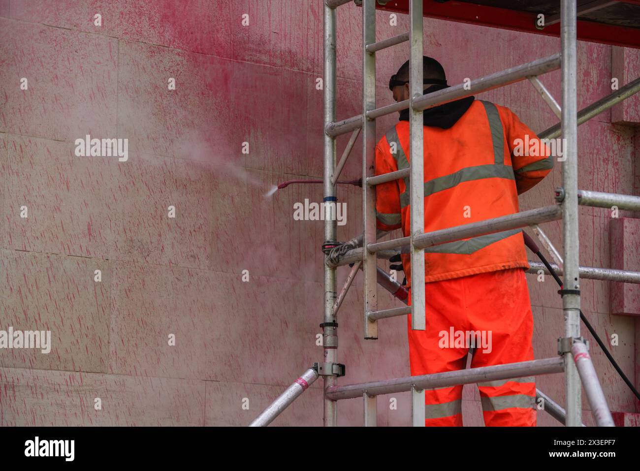 London, UK. 26th April, 2024. A worker washes the red paint with a