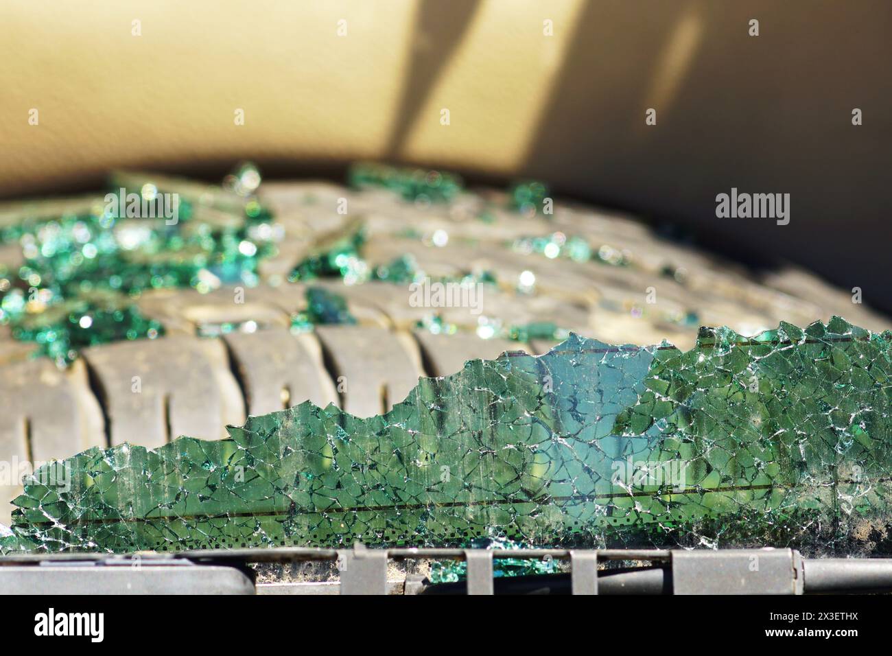 A cracked rear window of a car and glass shards lying on a spare tire in the background Stock Photo