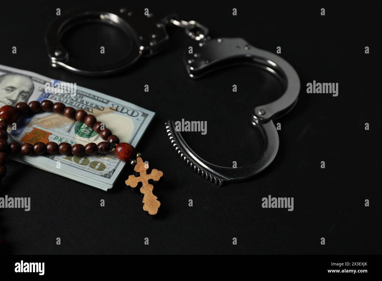 Dollars, handcuffs and prayer beads on black table Stock Photo