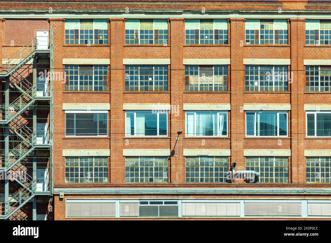 facade of old brick factors building with different windows and shutter blinds, closed, opend Stock Photo