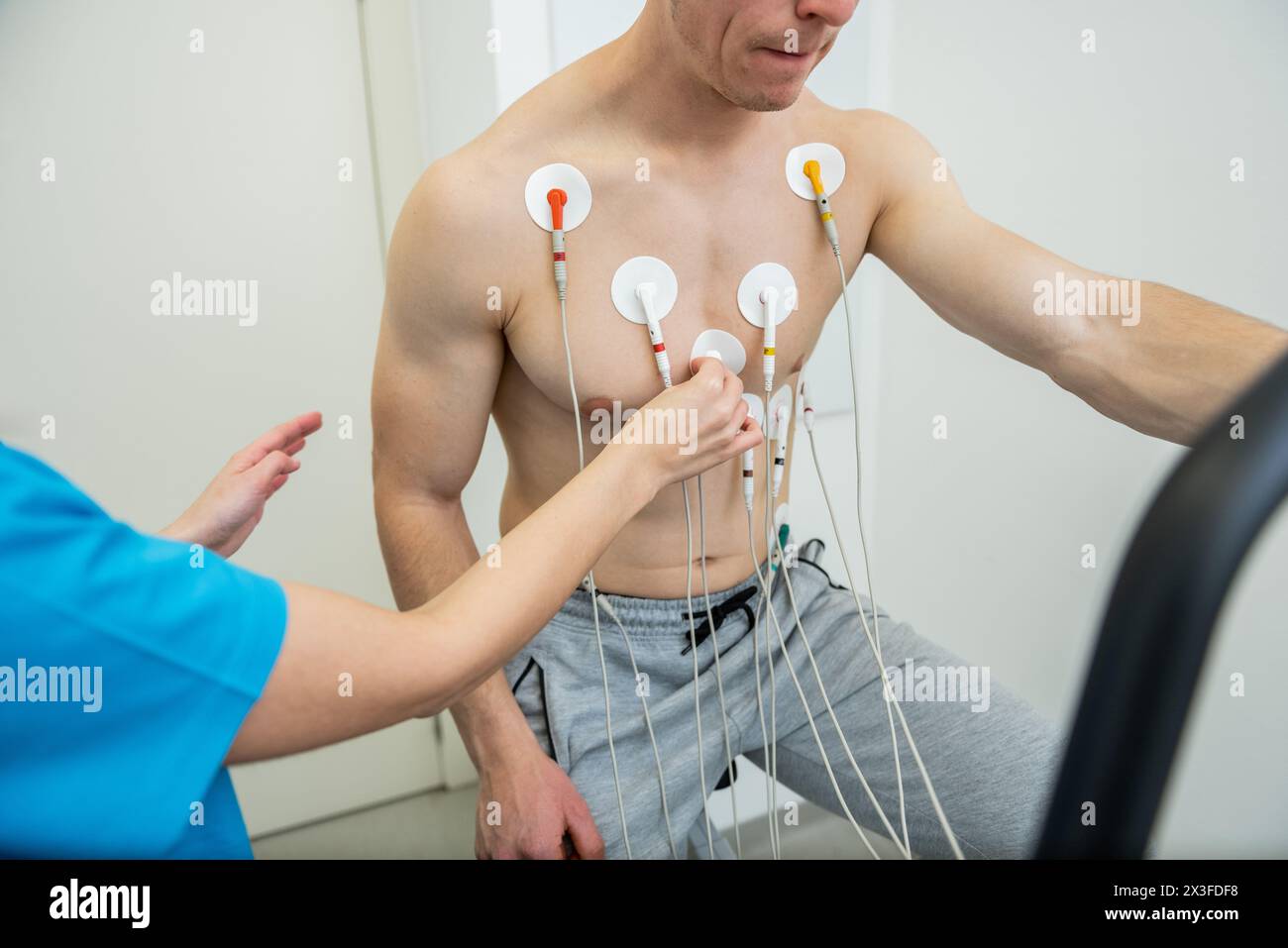 A patient undergoing a cardiac test with electrodes attached to their chest. Stock Photo