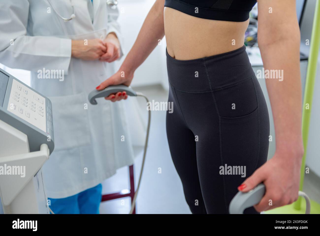 A health practitioner assists a woman with a body composition test using advanced equipment. Stock Photo