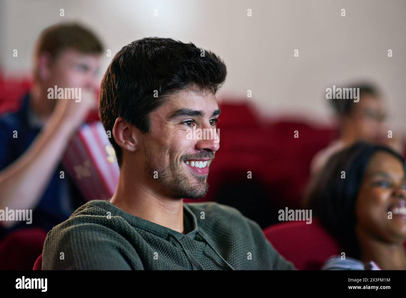 Happy, man and relax in cinema with movie screening to watch in theatre on holiday or vacation. Film, experience and people in audience enjoy funny Stock Photo