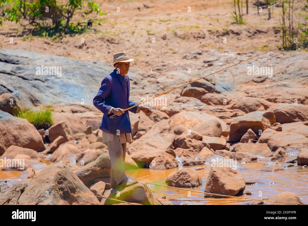 Antananarivo, Madagascar 07 oktober 2023. an elderly man catches fish for his daughter in a small stream Stock Photo