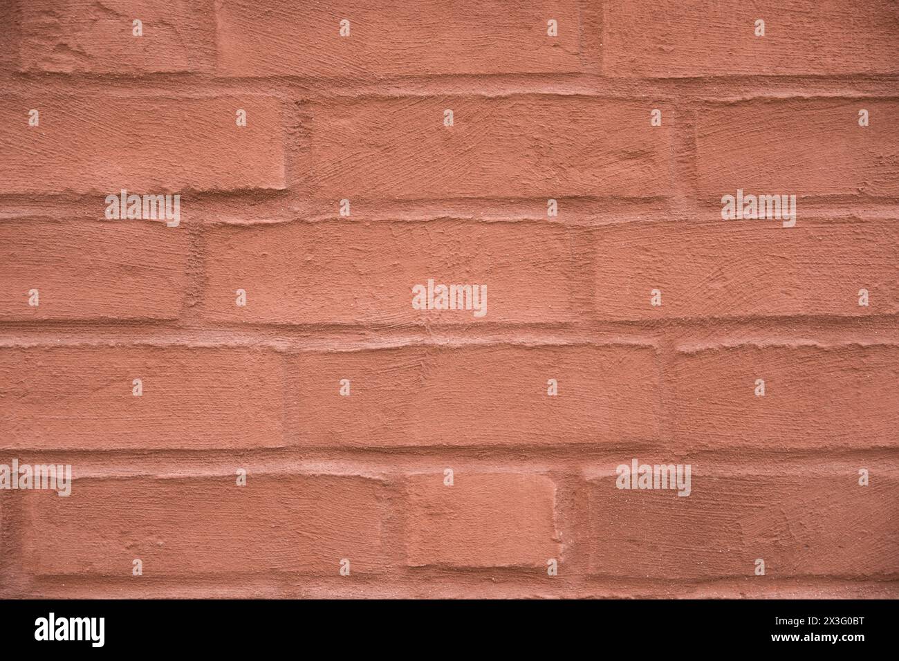 Red structural stone wall of the ancient building consists of small old dark bricks. Nature structural background. Stock Photo