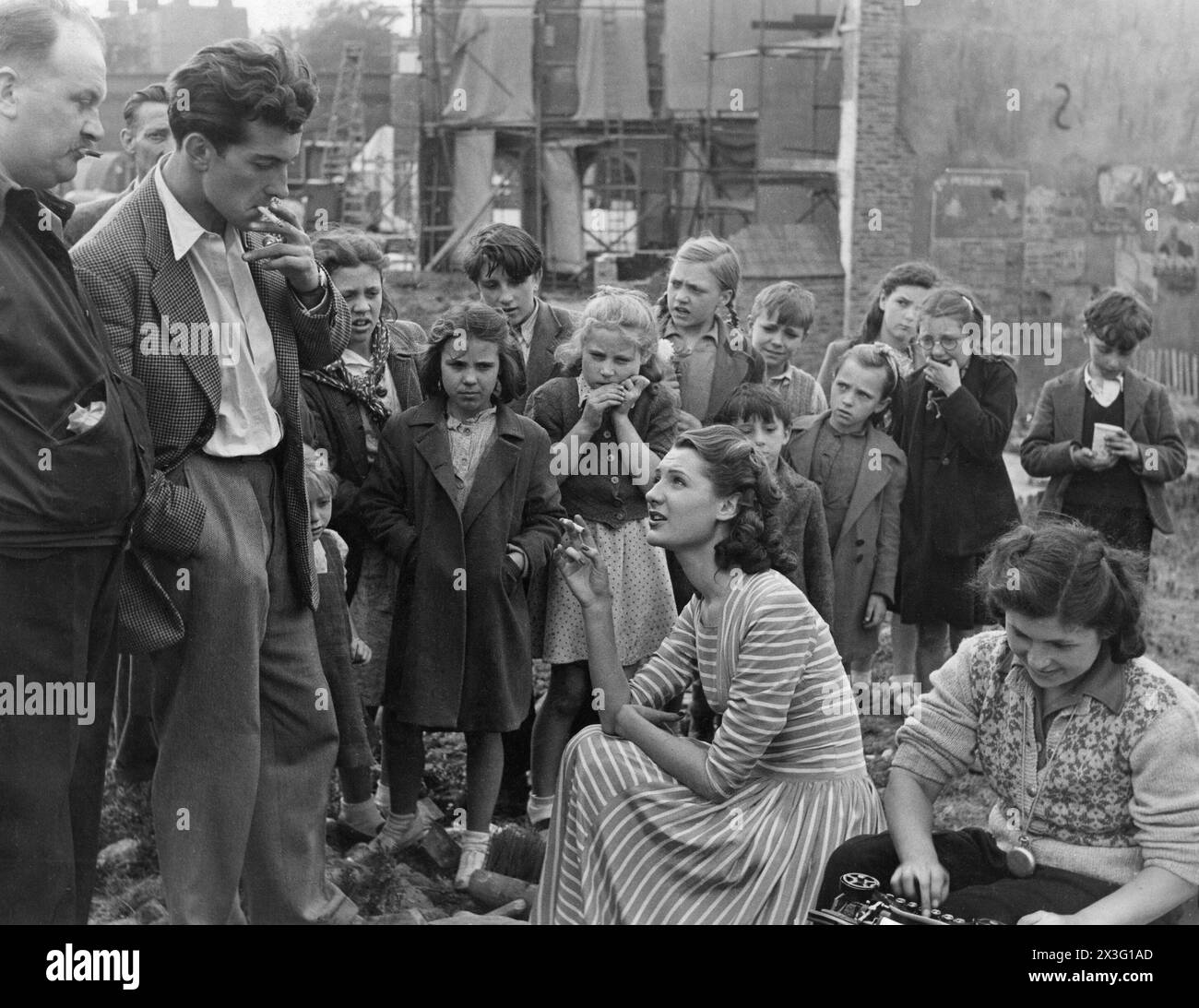 British Actress BARBARA MURRAY chatting with BERNARD FARREL  surrounded by local children during the making of the EALING  comedy PASSPORT TO PIMLICO 1949 filmed on location in a large bombsite in Lambeth Director HENRY CORNELIUS Screenplay T.E.B. CLARKE Music GEORGES AURIC Ealing Studios Stock Photo