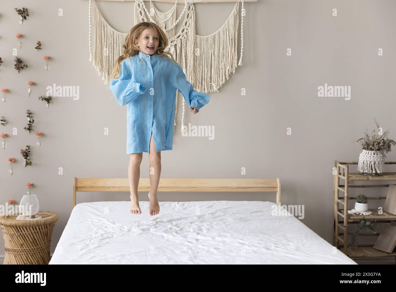 Happy little girl jumping on bed in modern bedroom Stock Photo