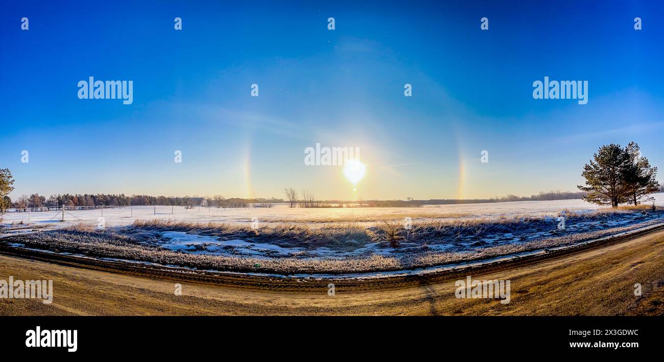 Atmospheric optical phenomenon sun dogs in the morning across a snow field.  Stock Photo