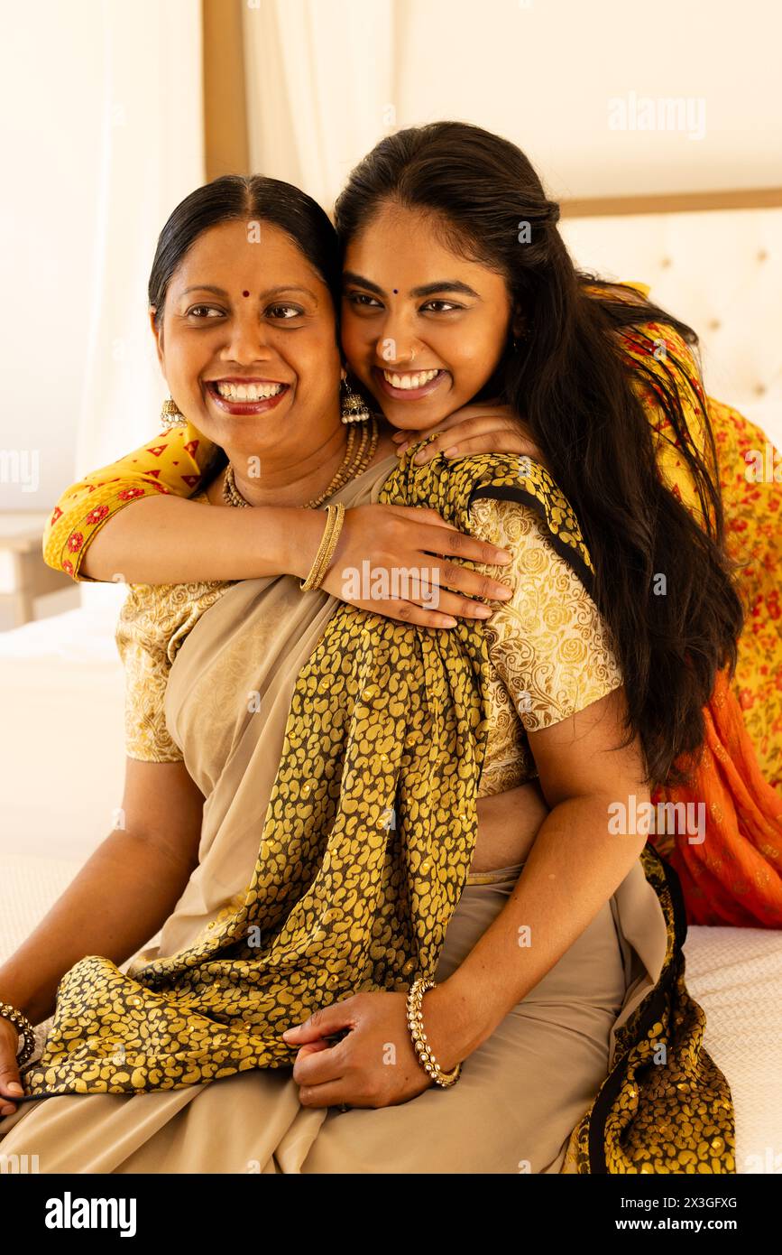 Indian mother, daughter in sarees embrace warmly at home Stock Photo
