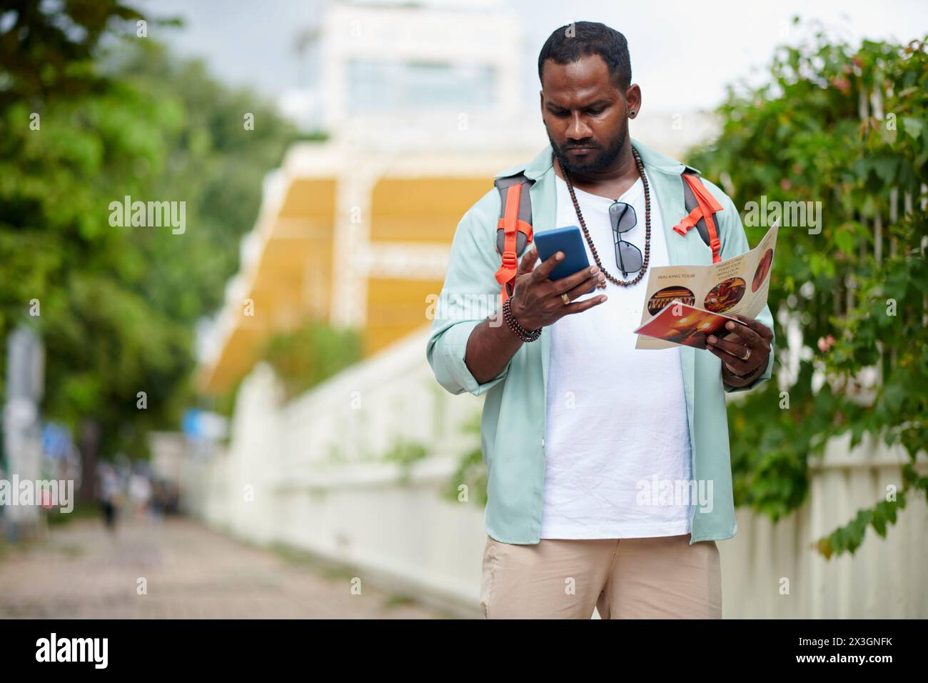 Young tourist with backpack looking at smartphone screen while using navigation application or local map during excursion Stock Photo