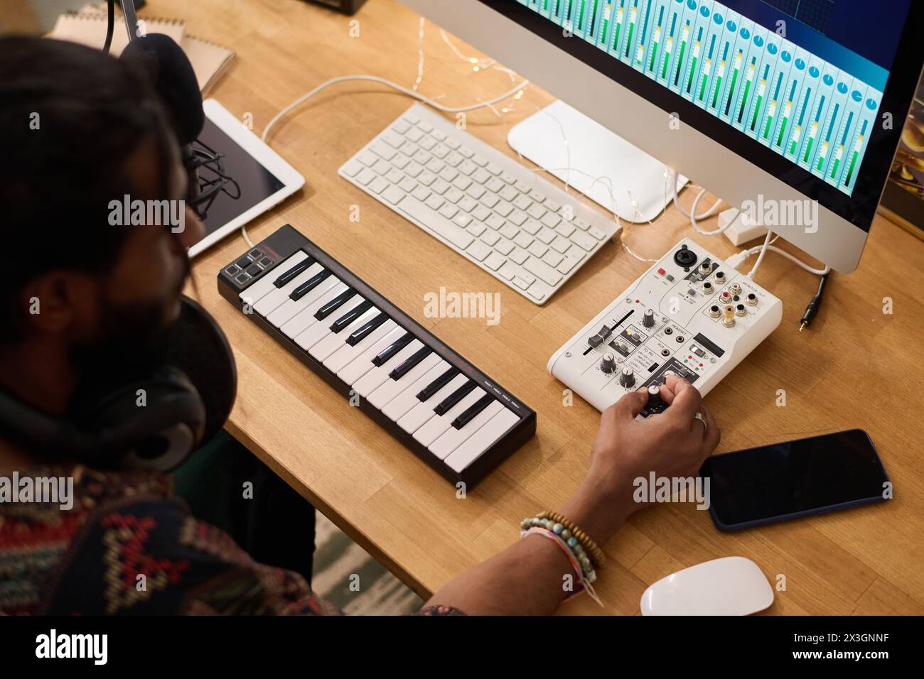 High angle of young creative artist turning consoles on sound mixing ...