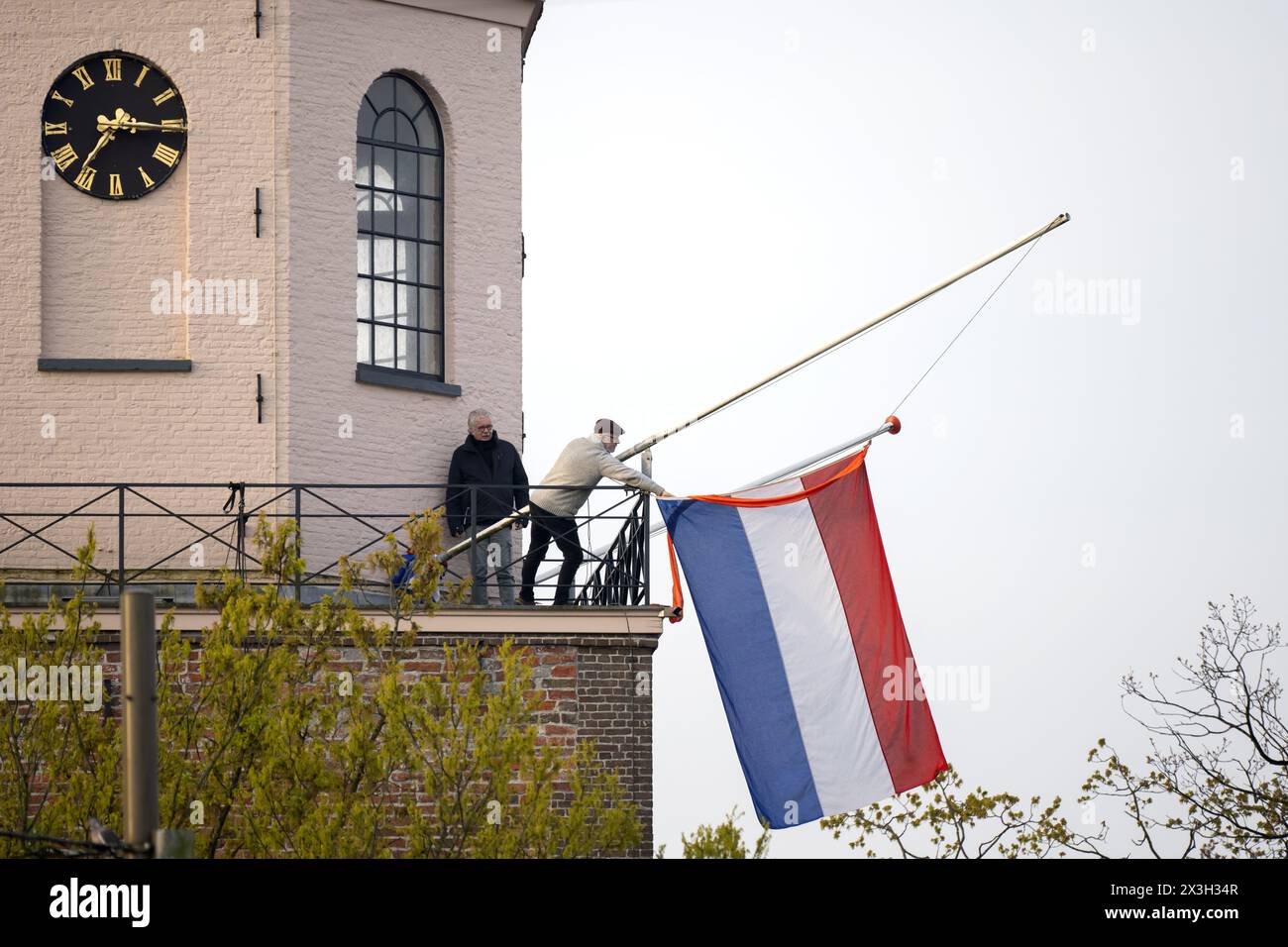 EMMEN - The Dutch flag is hoisted on the Grote Kerk for King's Day. While the royal family visits Emmen, the national holiday is also being fully celebrated in the rest of the country. ANP SANDER KONING netherlands out - belgium out Stock Photo