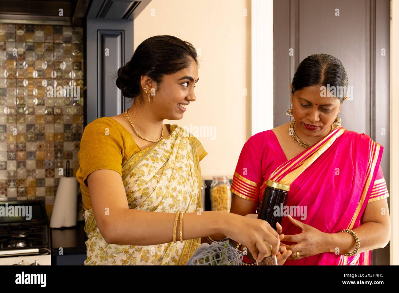 Indian mother and teenage daughter cooking together at home in kitchen Stock Photo