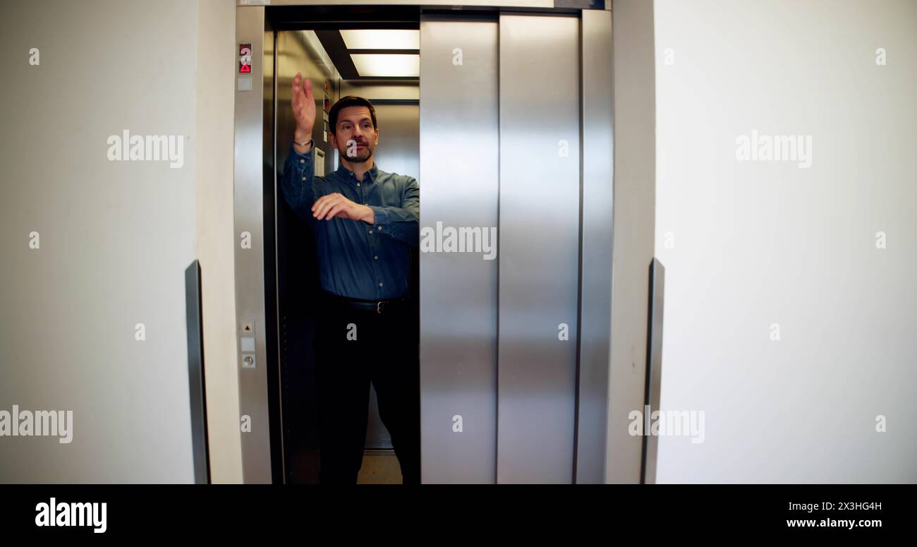Man Trying To Stop Door In Elevator Stock Photo