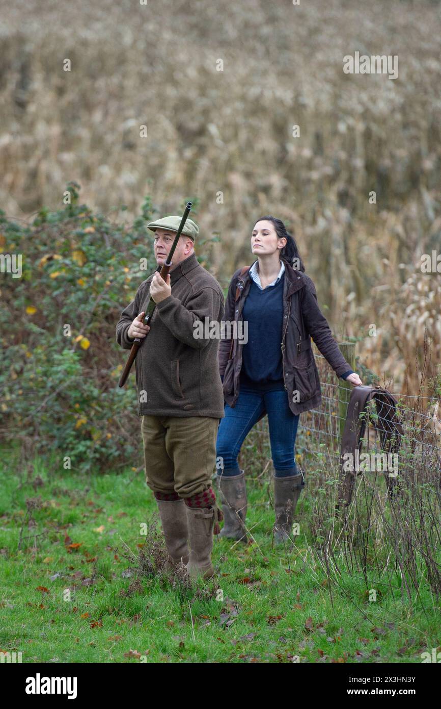 man shooting pheasants with girlfriend behind watching Stock Photo