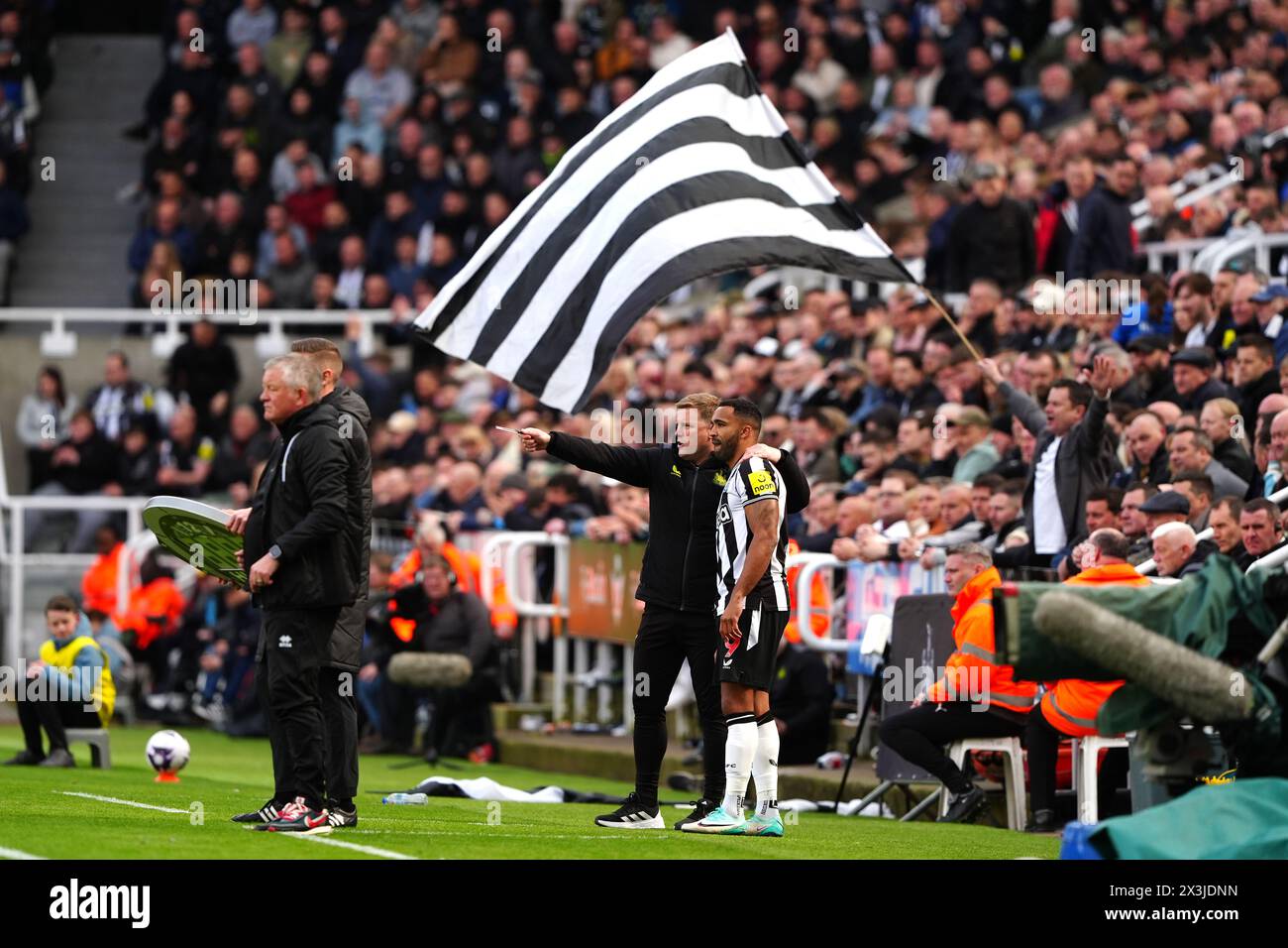 Newcastle United manager Eddie Howe (left) speaks with Newcastle United's Callum Wilson before being substituted on as a flag is flown above during the Premier League match at St. James' Park, Newcastle upon Tyne. Picture date: Saturday April 27, 2024. Stock Photo