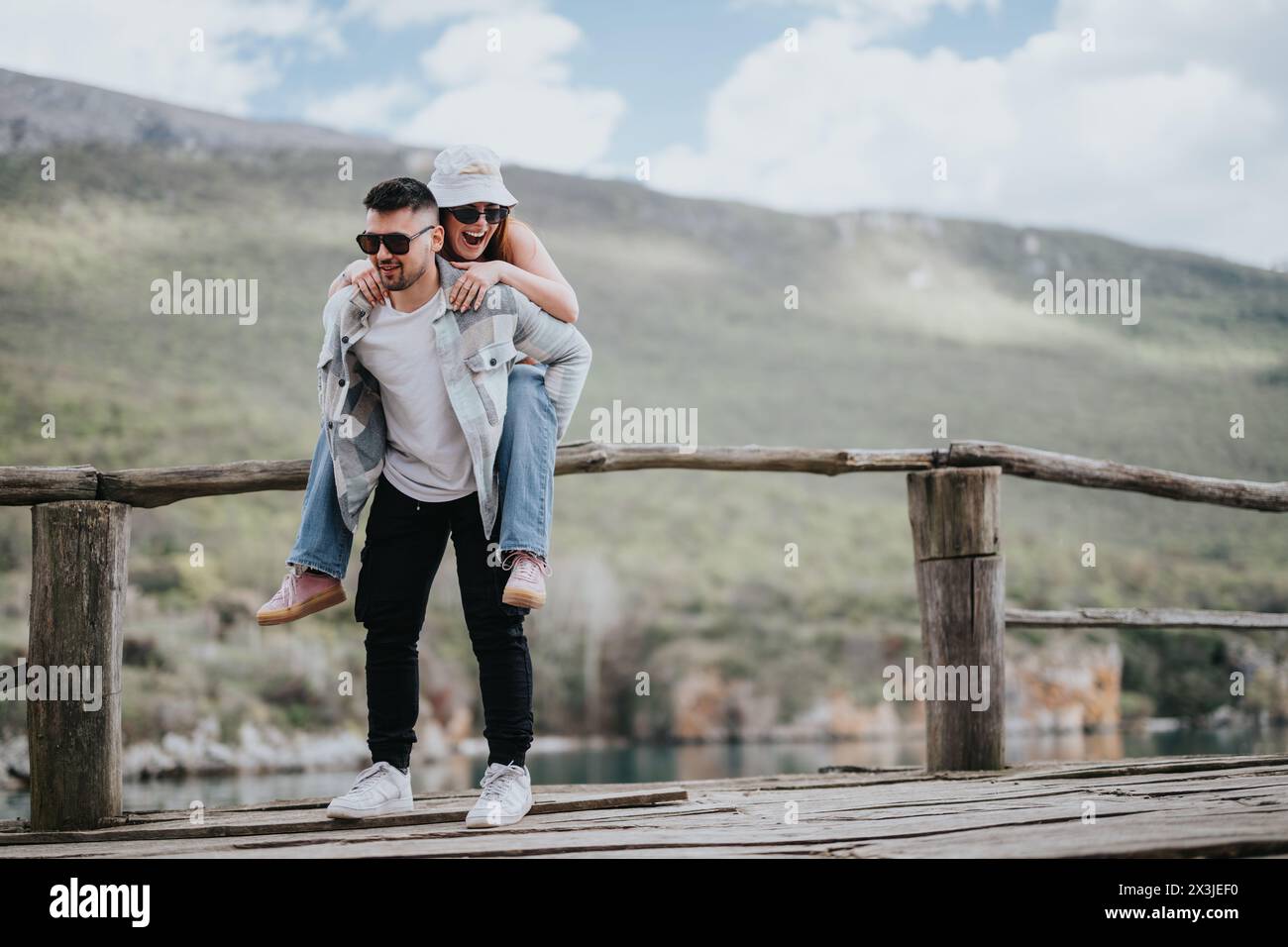 Joyful couple enjoying a piggyback ride on a scenic wooden bridge ...