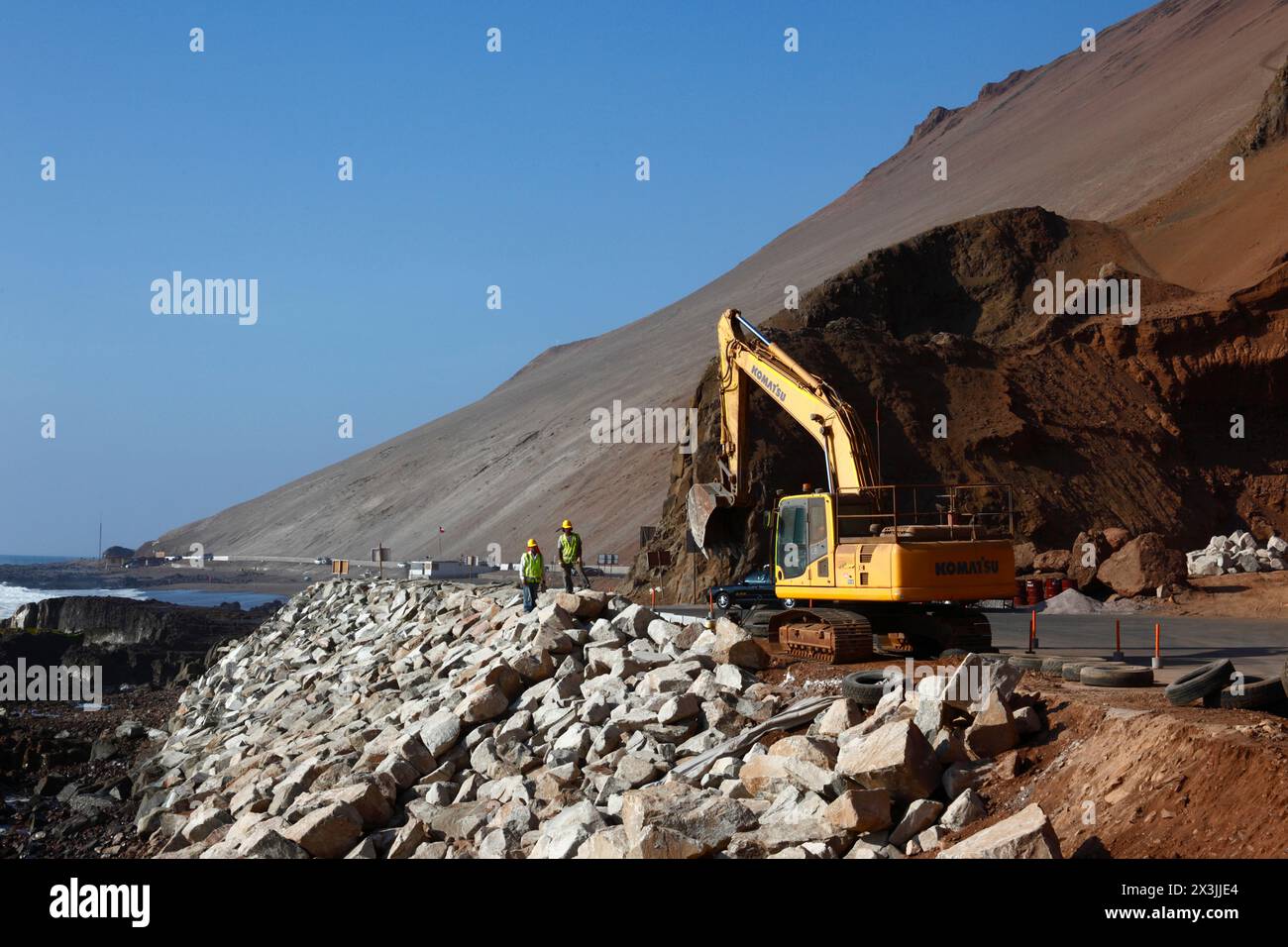 A Komatsu excavator working on a project to improve road access and parking facilities for the Cuevas de Anzota / Anzota Caves, near Arica, Chile Stock Photo