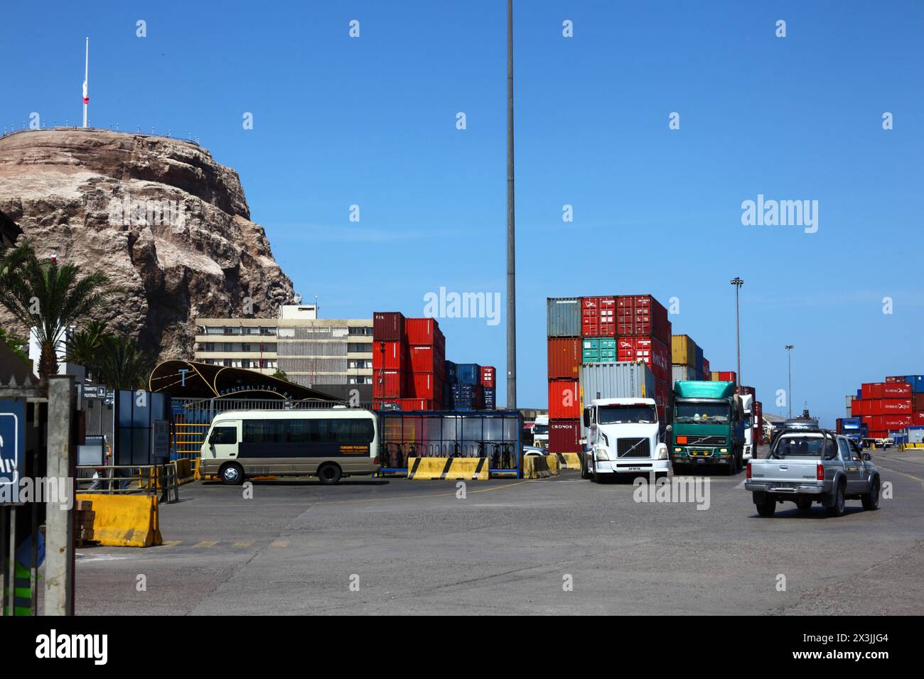 Trucks and containers stacked up in container port, El Morro headland on left hand side, Arica, Chile Stock Photo