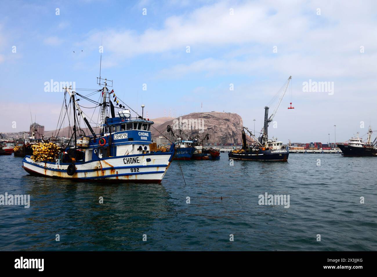 White Chine number 992 fishing trawler laden with equipment moored in port, El Morro headland in background, Arica, Chile Stock Photo