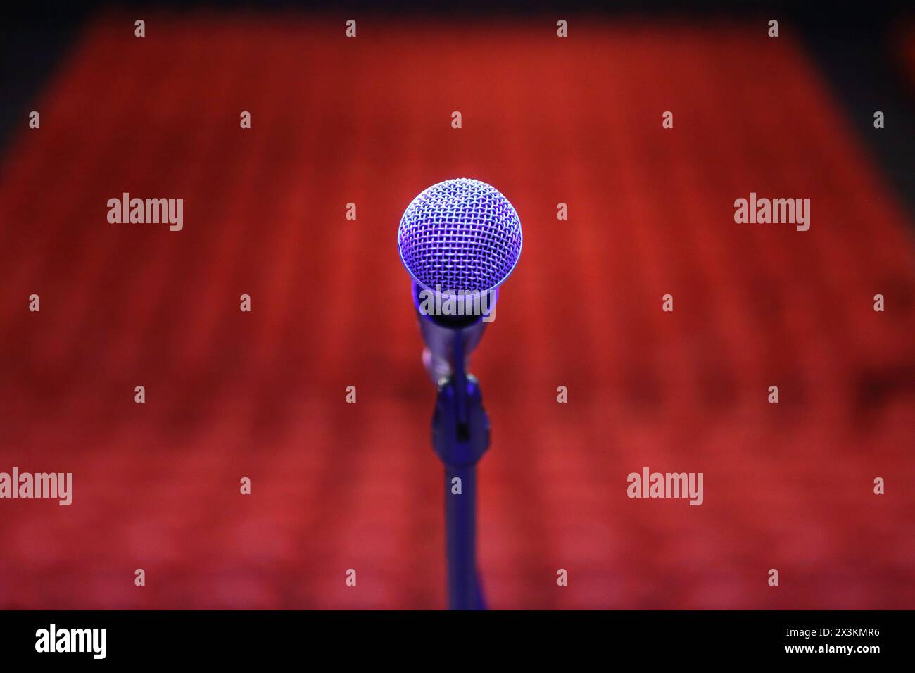 Microphone with red seats in auditorium in background - conept public speaking fear of public speaking performing in the spotlight Stock Photo