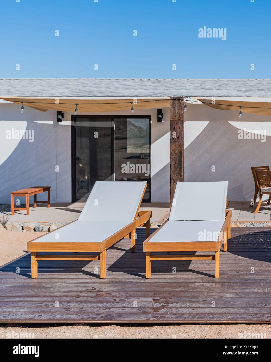 Two white wood outdoor chaise lounge chairs on a backyard deck Stock ...