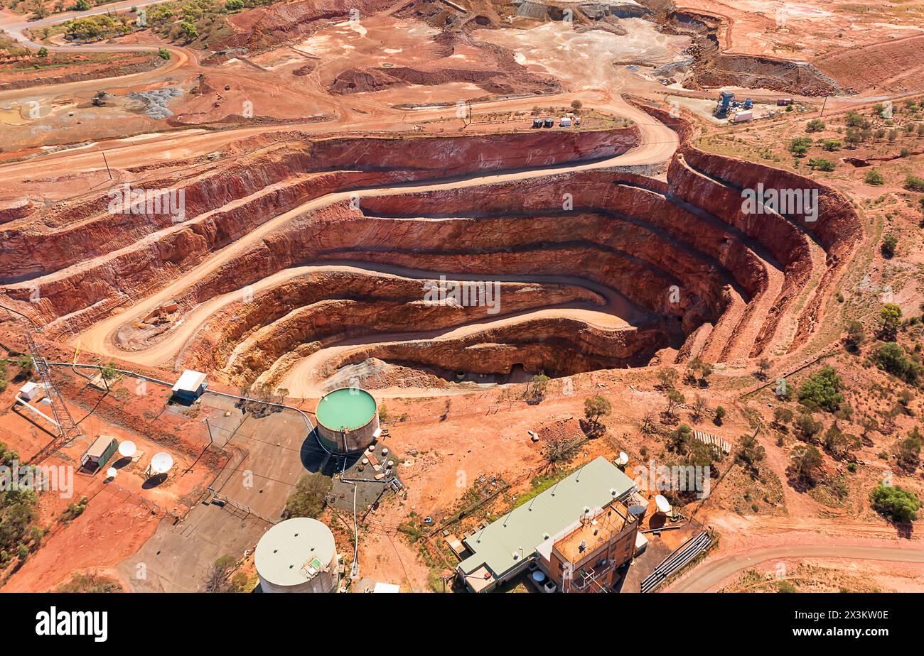 Red Australian OUtback soil in Cobar town with open pit copper mine - aerial top down view. Stock Photo