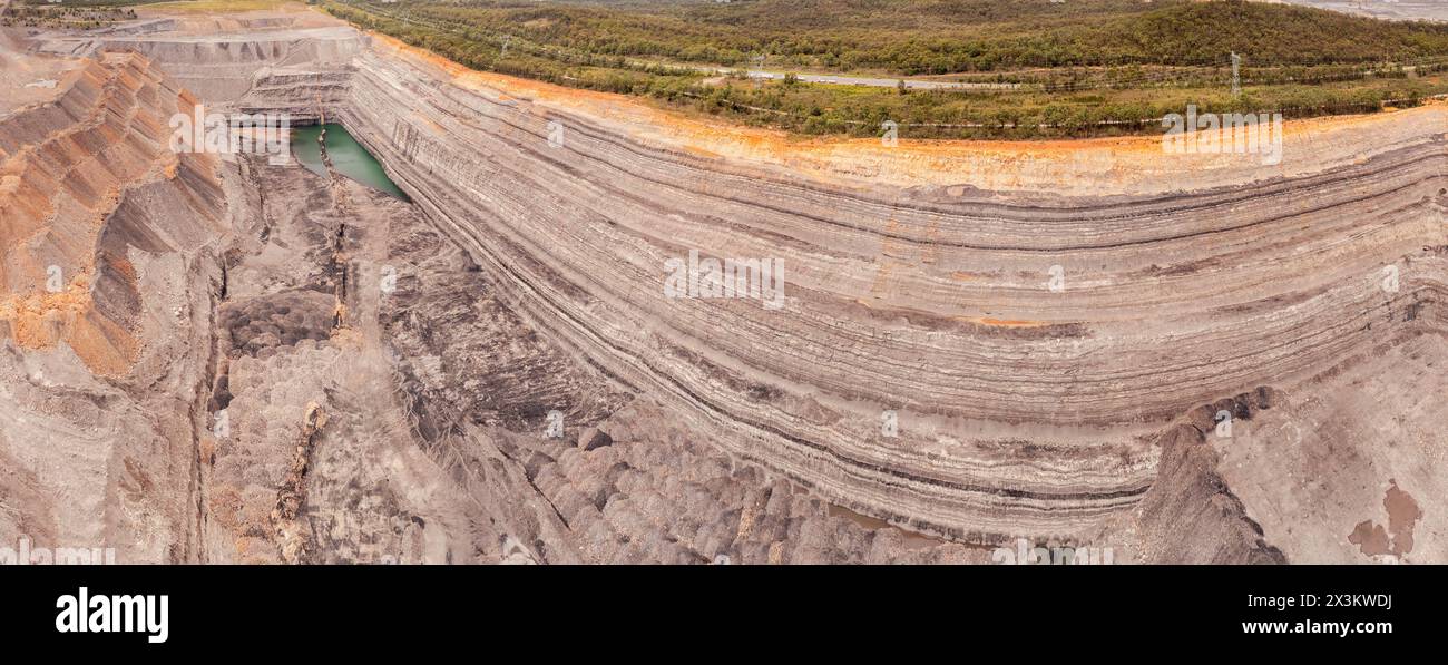Layered deep open pit excavated mine in Hunter valley of Australia - aerial panorama. Stock Photo