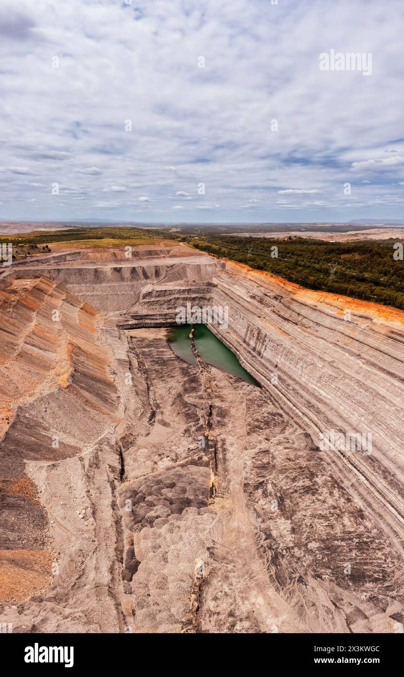 Huge open pit black coal iron ore mine in Hunter Valley of Australia - aerial vertical panorama. Stock Photo