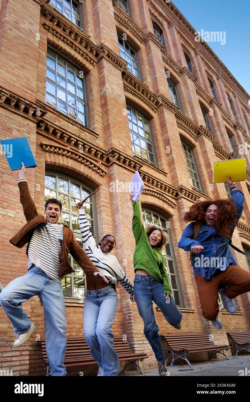 Happy group of multiethnic students celebrating the last day of school, jumping and raising arms. Stock Photo
