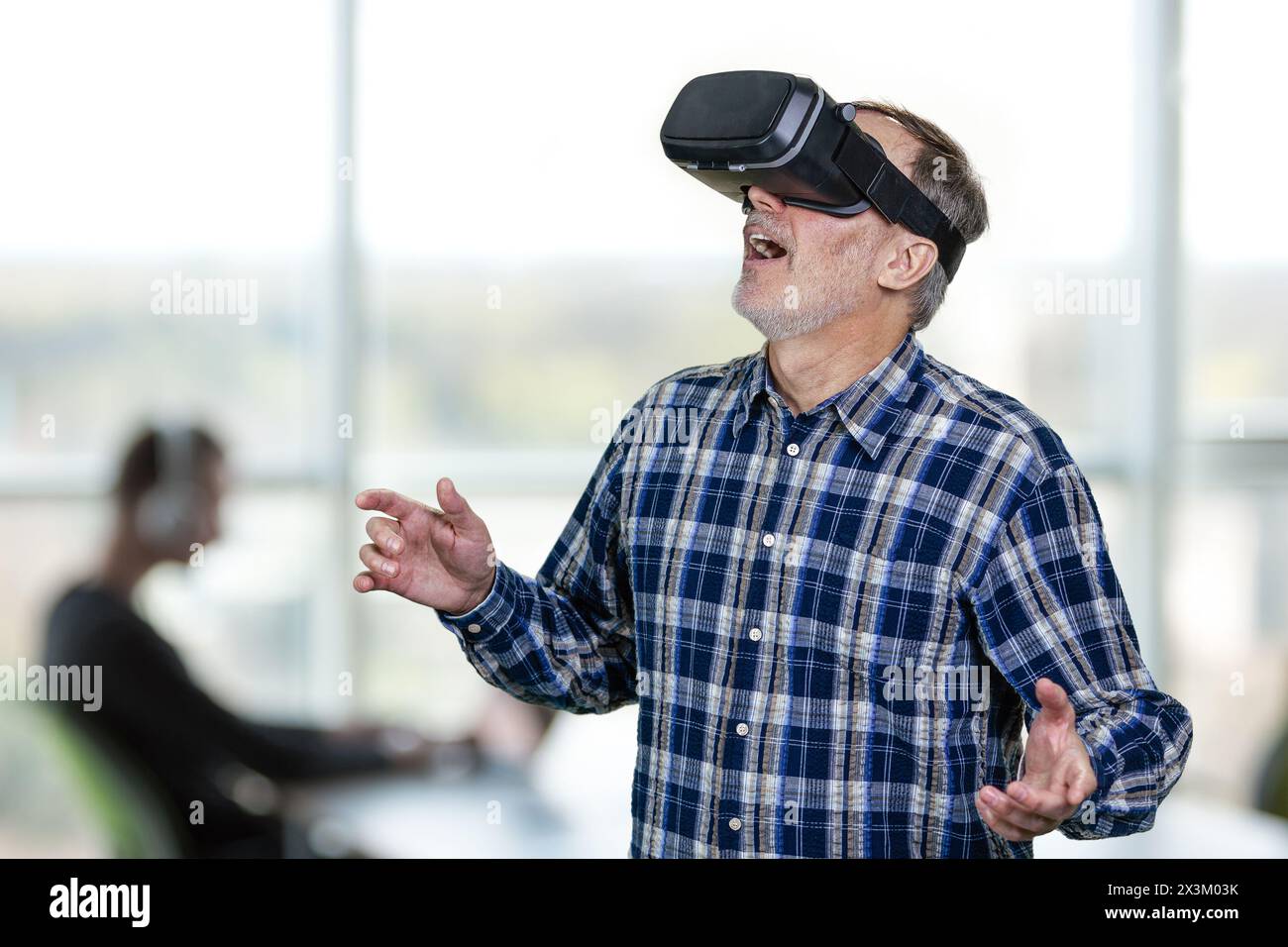 Excited elder man wearing vr headset with his mouth open. Indoor office enviroment background. Stock Photo