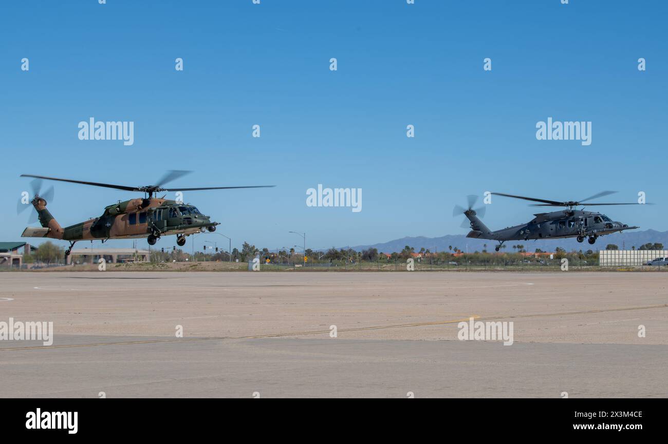An HH-60W Jolly Green II helicopter and an HH-60G Pave Hawk helicopter, both assigned to the 943d Rescue Group, hover above the flight line at Davis-Monthan Air Force Base, Arizona, during a routine training mission April 7, 2024. This HH-60G has a two-tone camouflage pattern paint scheme, consisting of drab green and tan colors, as part of a heritage restoration project honoring the history of Air Force Rescue during the Vietnam War. The HH-60W is the successor to the HH-60G and is used for a variety of missions to include combat search and rescue operations in hostile or denied territory. Th Stock Photo