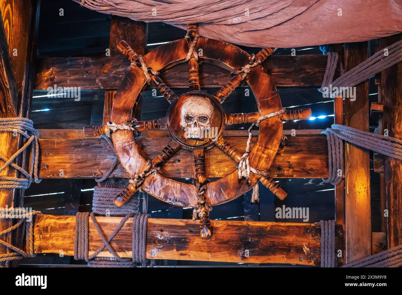 wooden steering wheel with a skull in captain's cabin on an ancient medieval pirate ship Stock Photo