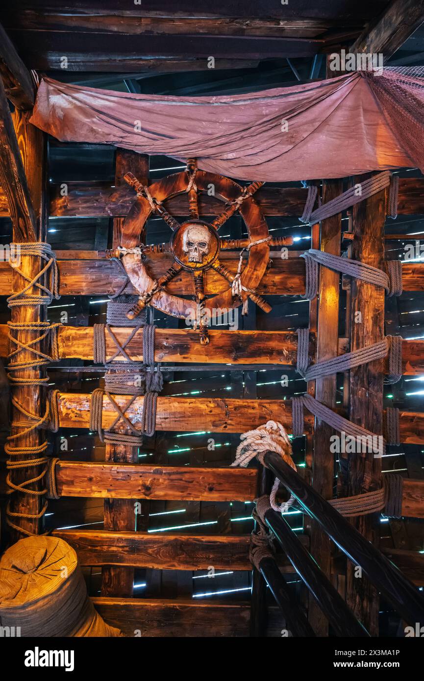 interior of cabin on ancient medieval wooden pirate ship with a steering wheel with a pirate's skull logo Stock Photo