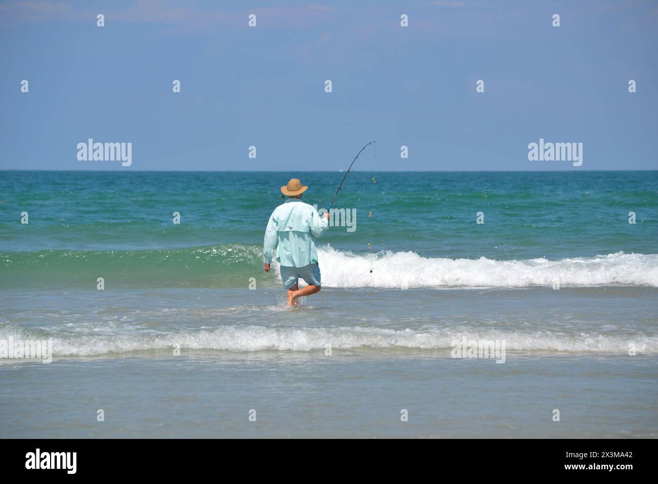 At Ponce Inlet, Jetty Beach, Florida, a surf fisherman strides into the