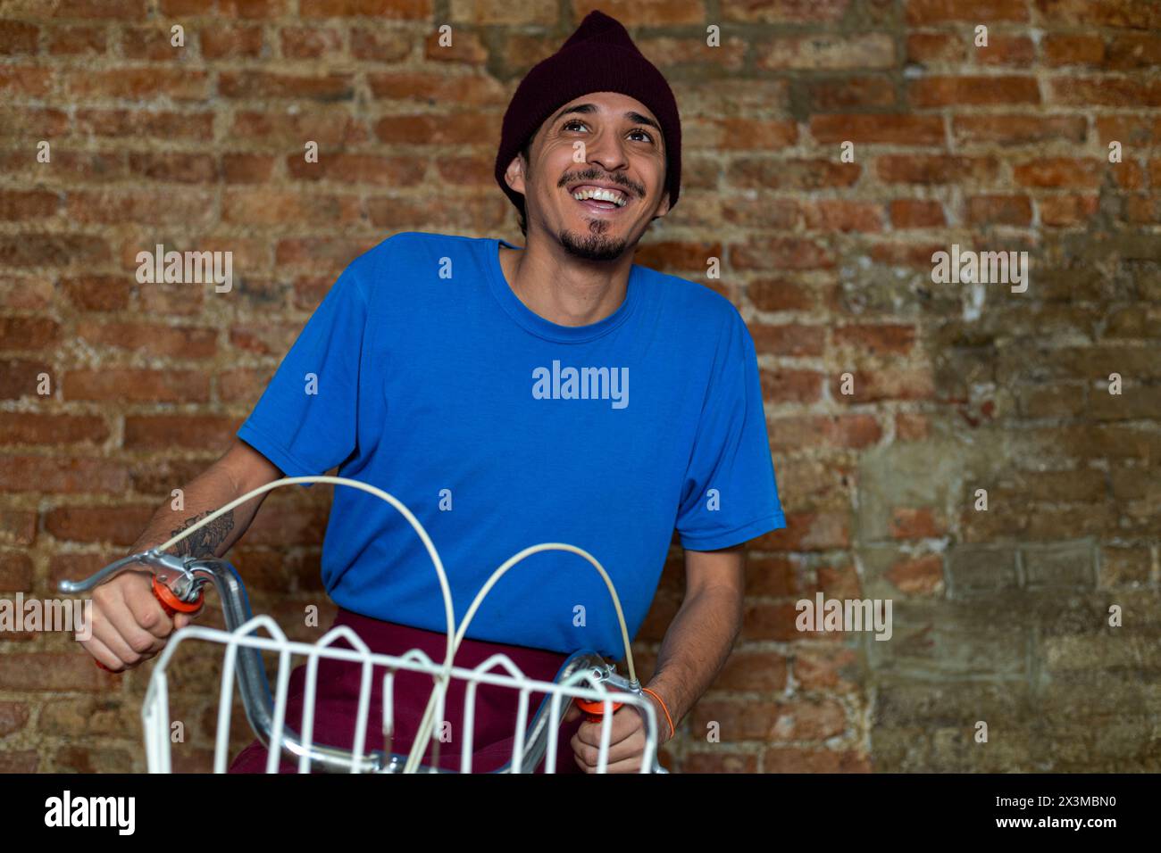 Hispanic Man Riding Bike Young Latino man (28) riding a bicycle with basket smiles as he rides ...