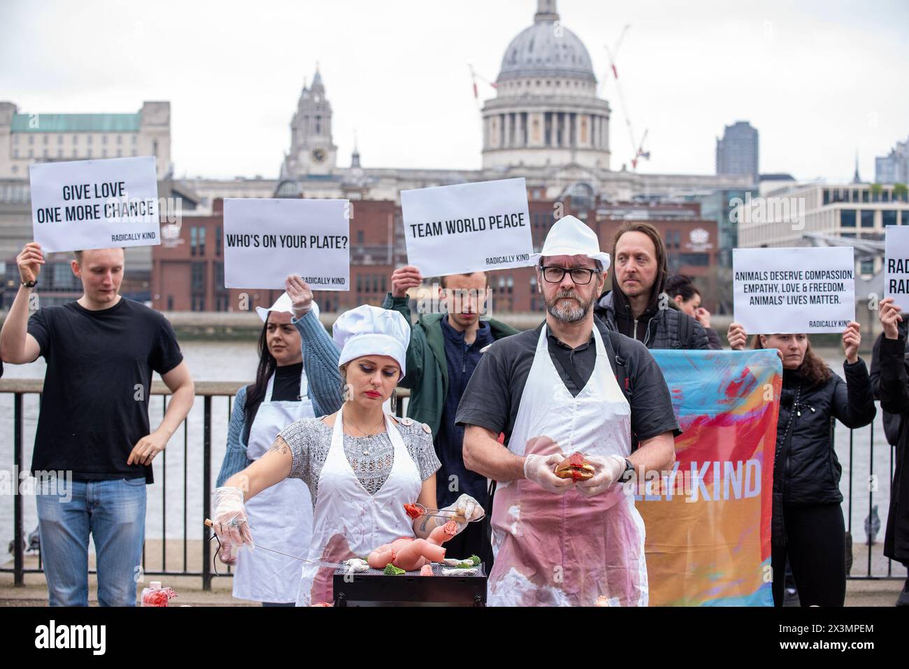 London, UK. 27th Apr, 2024. (EDITORS NOTE: Image contains graphic content)A female protester dressed as a chef barbeque a baby doll that symbolising a baby animal during the rally. Radically Kind is vegan organisation. They believe in animal rights and they want to stop animal suffering. They staged a protest outside the Tate Modern in London to make the people realise they eat baby animals very often. Credit: SOPA Images Limited/Alamy Live News Stock Photo