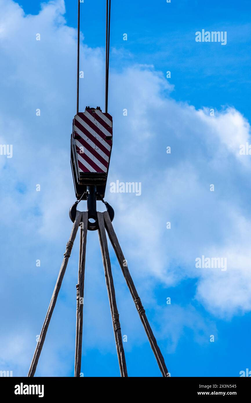 Detail shot of a hook of a crane with steel cables against a cloudy sky Stock Photo