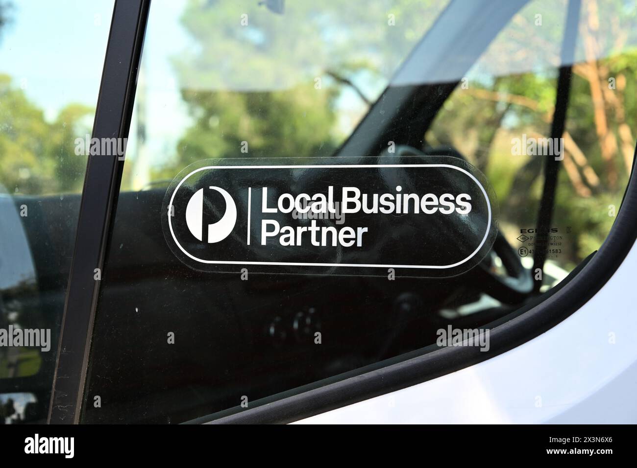 White Australia Post local business partner sticker in the window of a white delivery or courier van Stock Photo